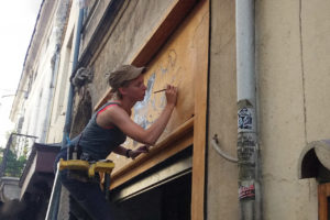 L'illustratrice Eléonore Ampuy en train de peindre une façade
