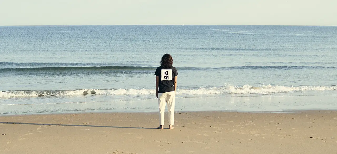 Homme de dos sur la plage de l'Uhabia à Bidart avec un tee shirt dessiné par l'artiste américain James Coffman pour Bask in the Sun